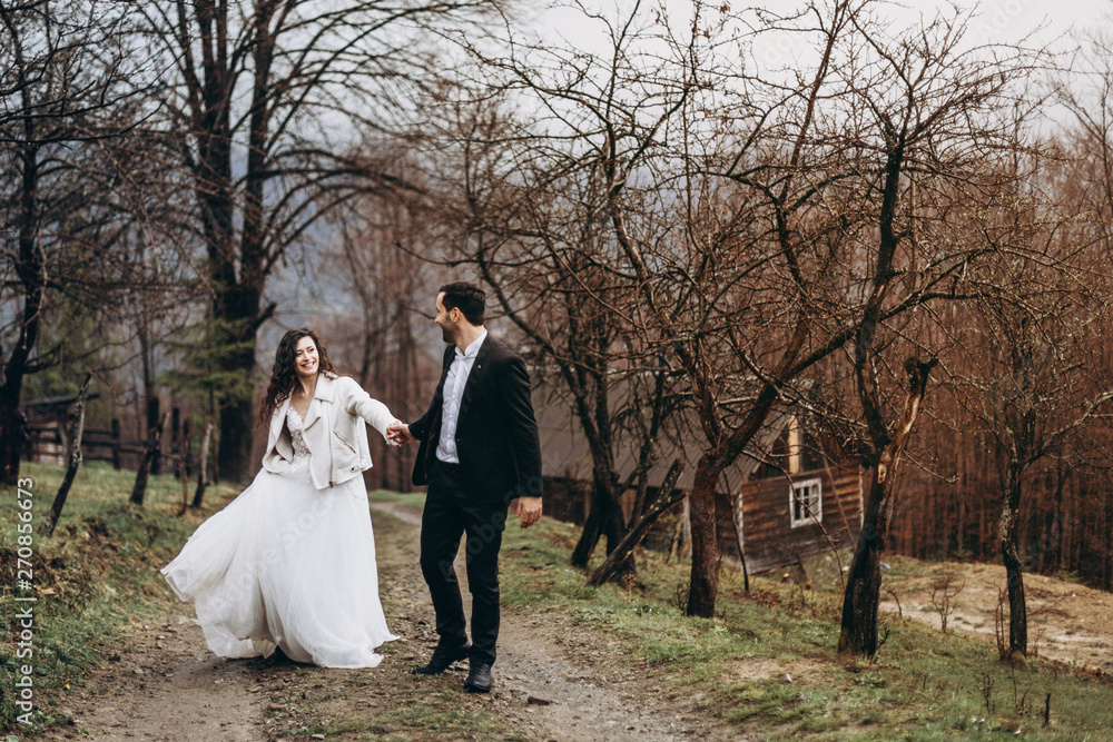 walk of a husband and wife in a forest in the middle of the mountains. Cute Bridesmaid Newlyweds enjoy a wedding day, a husband leads a wife walk of a husband and wife in a forest in the middle of the mountains. Cute Bridesmaid Newlyweds enjoy a wedding day, a husband leads a wife