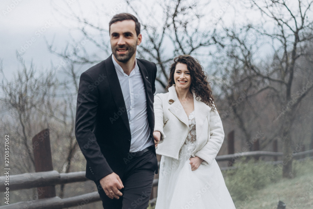 Stylish couple of brides in a wedding walk during a cloudy weather in the mountains. Fog and mist, but the brides are happy and smiling at the wedding photo shoot