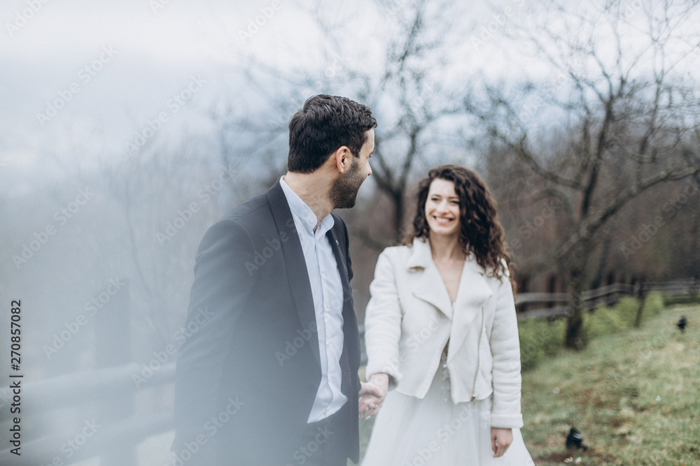 Stylish couple of brides in a wedding walk during a cloudy weather in the mountains. Fog and mist, but the brides are happy and smiling at the wedding photo shoot Stylish couple of brides in a wedding walk during a cloudy weather in the mountains. Fog and mist, but the brides are happy and smiling at the wedding photo shoot