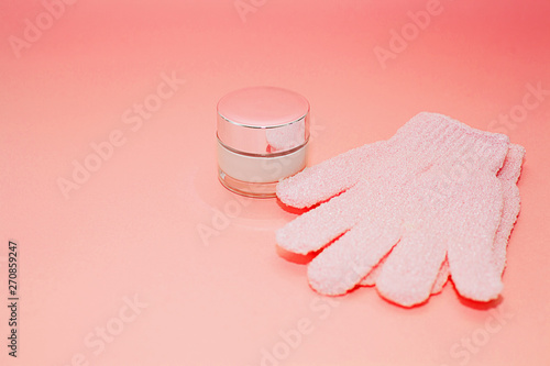 Beauty luxury cosmetic cream container and bath massage gloves on color of the year 2019 - Living Coral background. Background with facial cosmetic products. Package for cream. Beauty and spa concept