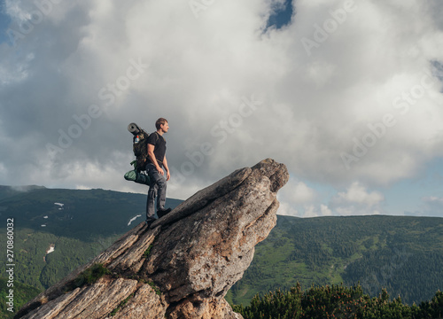 The guy is standing on a rock in the mountains
