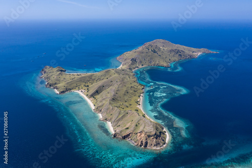 Seen from a bird's eye view, an idyllic island is surrounded by a healthy coral reef in Komodo National Park, Indonesia. This tropical area is known for its marine biodiversity as well as its dragons.