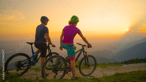 COPY SPACE: Mountain bikers sit on their bikes and watch the beautiful sunset.