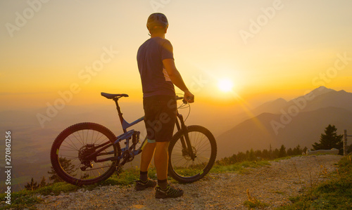 COPY SPACE: Unrecognizable man watches the sunrise before a mountain bike ride.