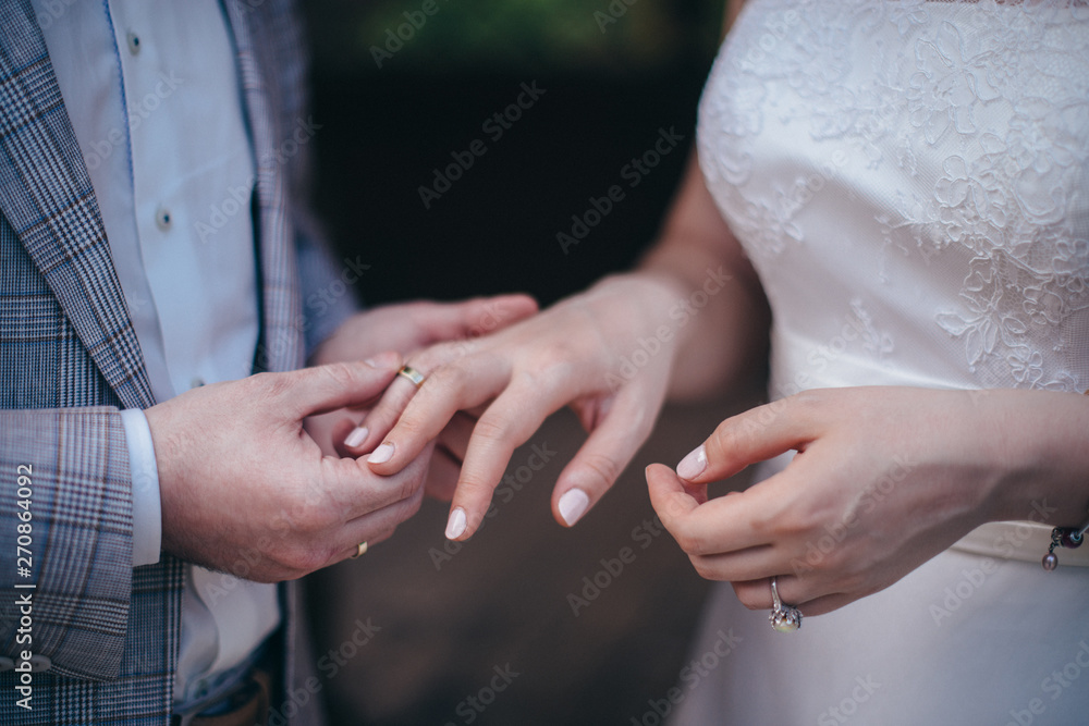 A couple of newlyweds at the wedding ceremony wear wedding rings to each other.