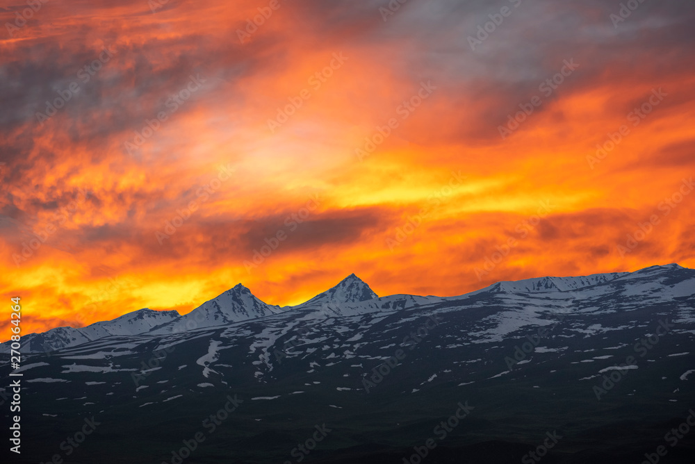 Fairy sunset. Beautiful orange sky with colorful clouds over the mountains. Armenia Aragats mountains.