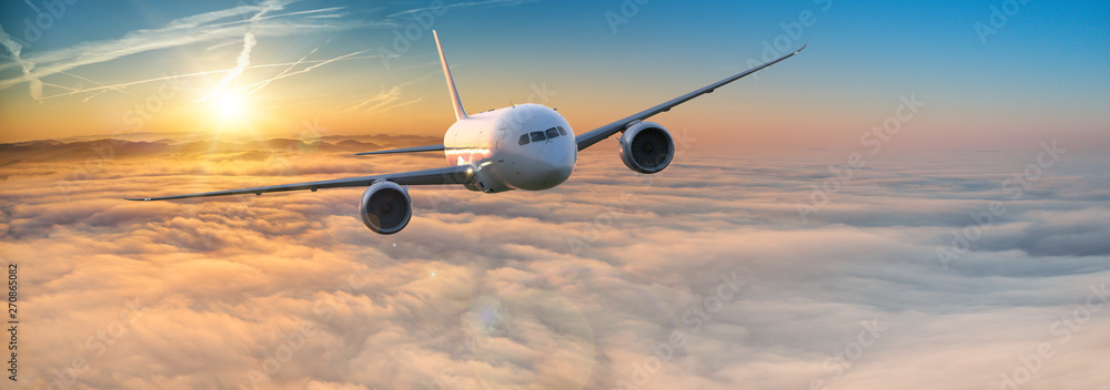 Fototapeta premium Commercial airplane jetliner flying above dramatic clouds in beautiful light. Travel concept.