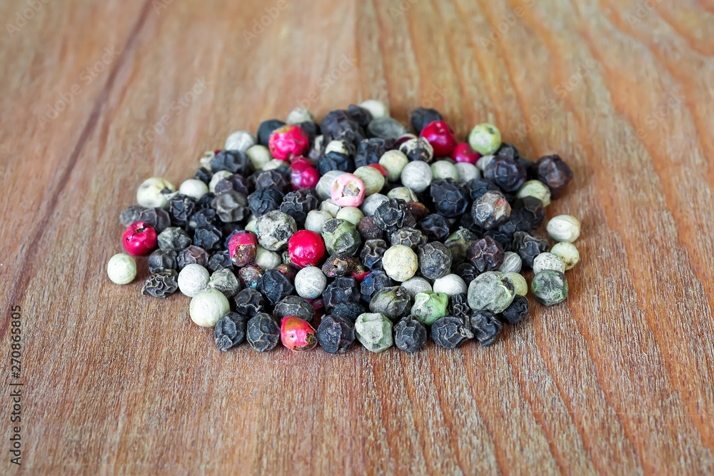 Heap of peppercorn melange. White, black, red and green pepper grains on a brown wooden cutting board. Natural food spices and seasonings. Tasty eating. Heap of peppercorn melange. White, black, red and green pepper grains on a brown wooden cutting board. Natural food spices and seasonings. Tasty eating.