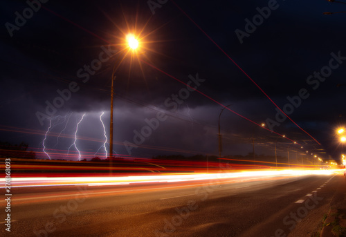 Discharges of lightning in the night sky over the road