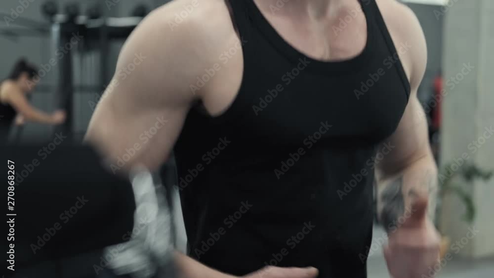 Close up of Young redhead athletic man exercising and running on treadmill in sport gym. Bearded man running on treadmill machine in sport gym in slow motion in UHD