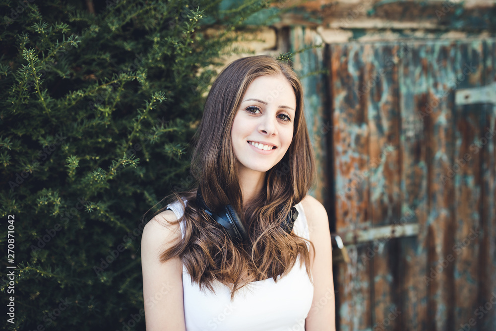 Fototapeta premium Young woman at the country side with headphones outdoors, smilling