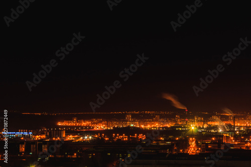 City downtown at night.City skyline in the dusk. Amazing panoramic view of modern city. Aerial view of residential flats of dormitory area close to industrial zone  factory pipes with smoke