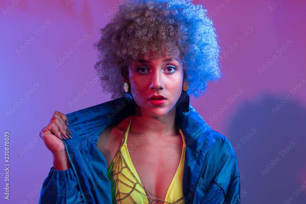 Funky young black woman with neon colored bikini modeling in studio lights setting, with blue windbreaker jac Funky young black woman with neon colored bikini modeling in studio lights setting, with blue windbreaker jac
