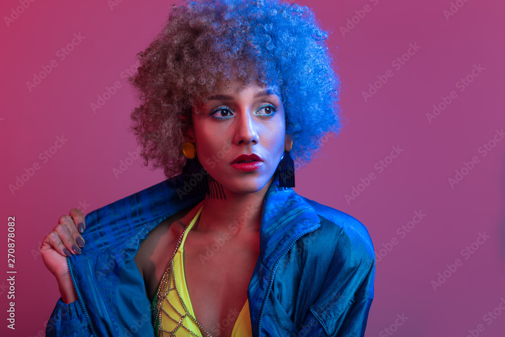 Funky young black woman with neon colored bikini modeling in studio lights setting, with blue windbreaker jac Funky young black woman with neon colored bikini modeling in studio lights setting, with blue windbreaker jac