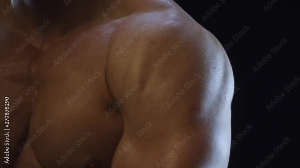 Young fit guy posing, showing shoulder muscles, slow motion Young fit guy posing, showing shoulder muscles, slow motion