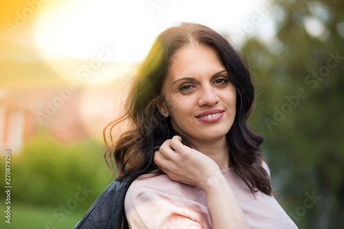 Beautiful middle-age woman in black leather jacket smiling broadly enjoying life. Springtime, outdoors;