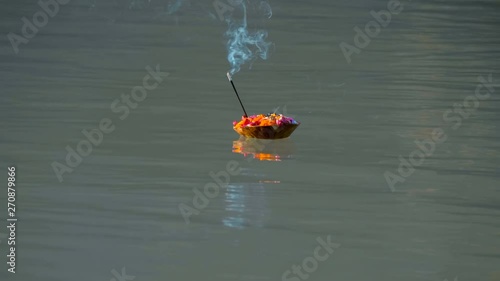 After traditional Indian religious ceremonies, a basket with flowers and smoking incense floats along the holy Ganges River
