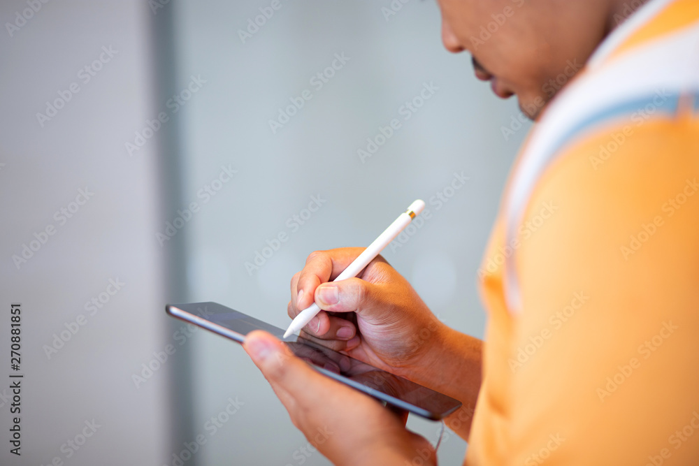 Hand holding stylus pen writing down on tablet Hand holding stylus pen writing down on tablet