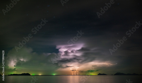 Flashing lightning through the clouds above the night sea with star.