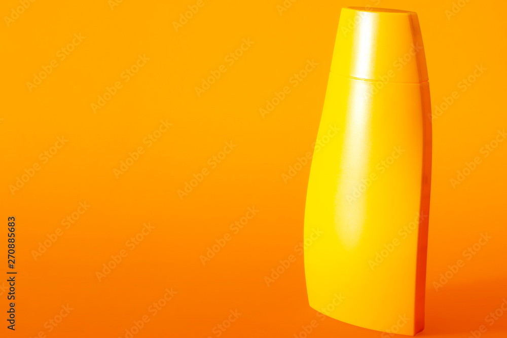 Protection against UVA and UVB rays, skincare products for sunny days and beach toiletries concept theme with a plastic bottle of suntan lotion isolated on orange background with copy space Protection against UVA and UVB rays, skincare products for sunny days and beach toiletries concept theme with a plastic bottle of suntan lotion isolated on orange background with copy space
