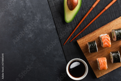 Set of sushi and maki rolls with sliced avocado on stone table photo