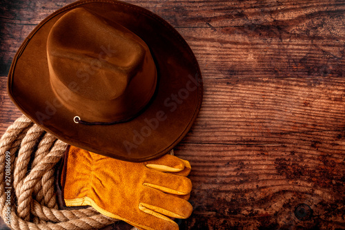 American culture, living on a ranch or farm and country muisc concept theme with a cowboy hat, rope lasso and rodeo leather gloves on a wooden background in a old saloon with copy space