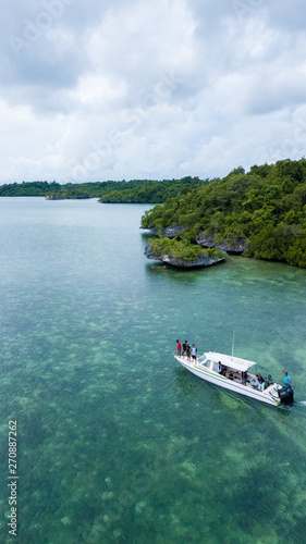 Aerial photography view of Wakatobi (Wangi-Wangi, Kaledupa, Tomia & Binongko) islands with a white boat, Southeast Sulawesi, Indonesia