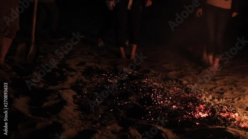 On a dark night in the light of a campfire, man prepares to pass over the embers