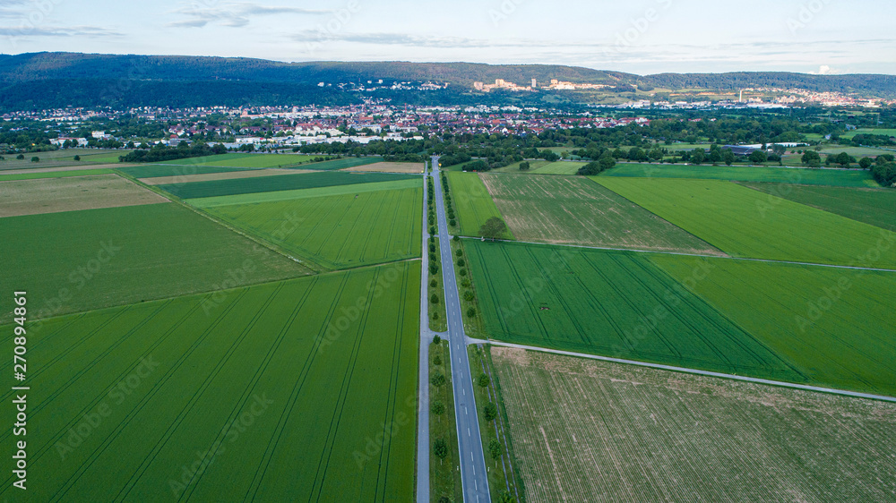 Aerial Capture of Countryside Landscape with Long Empty Road and City in Background