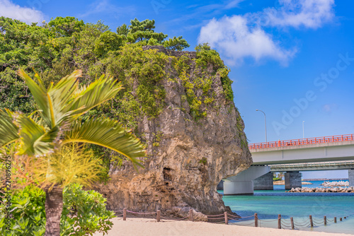 palm tree on the sandy beach Naminoue topped by a huge rock with a Shinto Shrine at the top of a cliff and a highway passing in Naha City in Okinawa Prefecture, Japan. photo