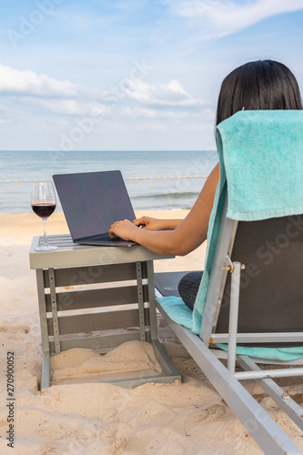 Woman typing on laptop by the beach © Quang