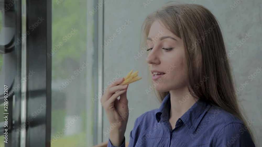 Beautiful girl holding fried potatoes at a fast-food restaurant Beautiful girl holding fried potatoes at a fast-food restaurant