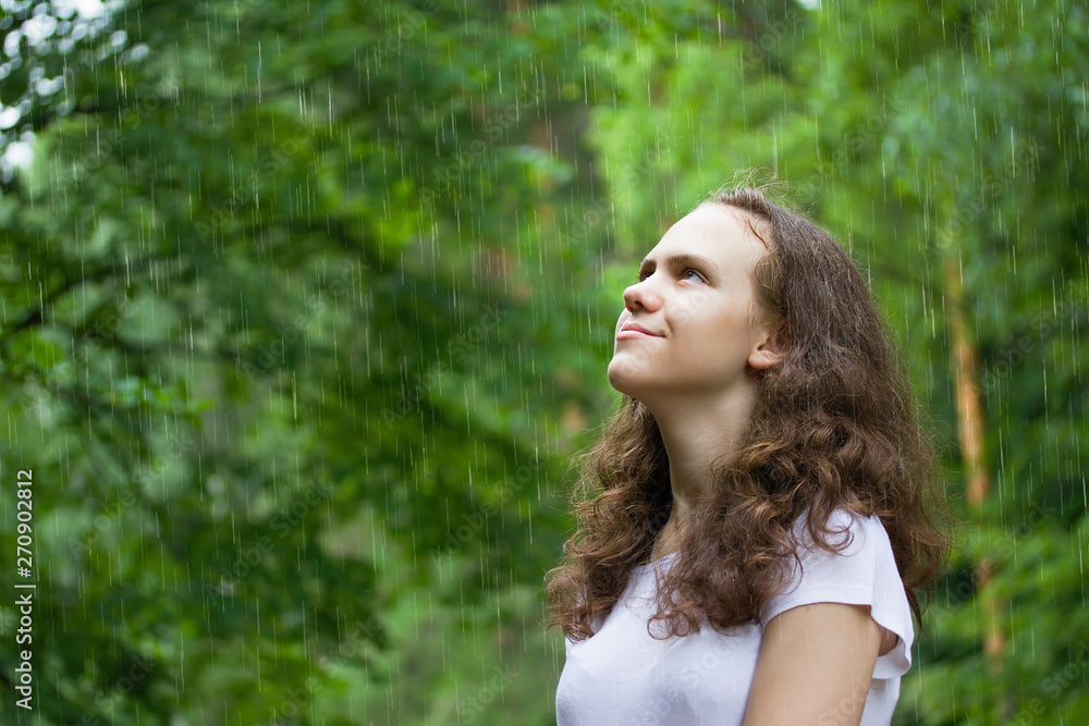 Naklejka premium young girl under the rain in a summer park