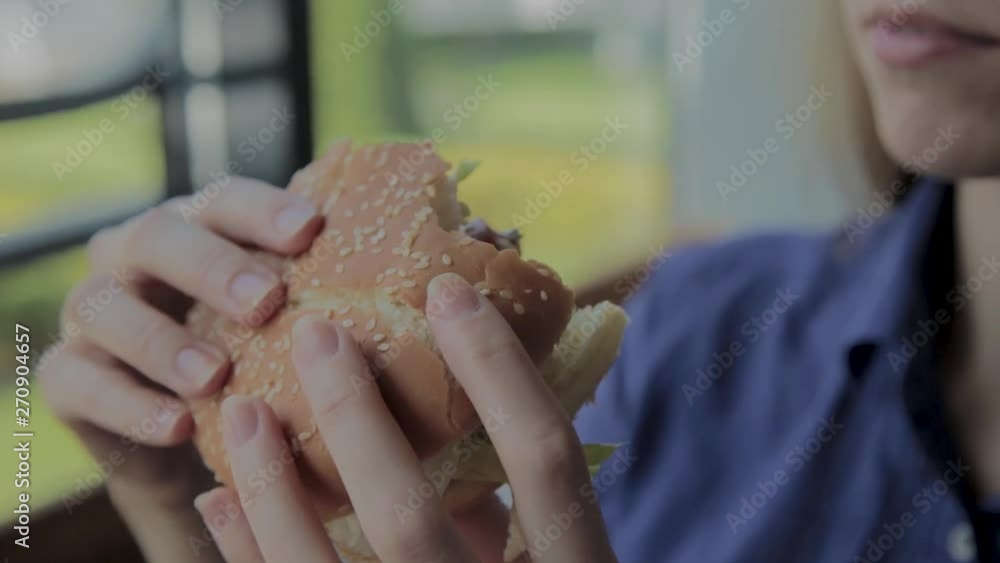 Beautiful girl eats a burger. Fast food restaurant Beautiful girl eats a burger. Fast food restaurant