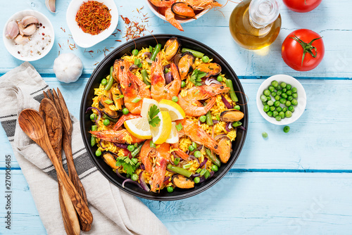 Traditional spanish seafood paella in the fry pan on a blue wooden table, top view.