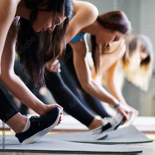 Leisure, sport, fitness, yoga class, relaxation, balance, flexibility. Fit women practicing yoga in studio. Stretching exercise for muscles warming