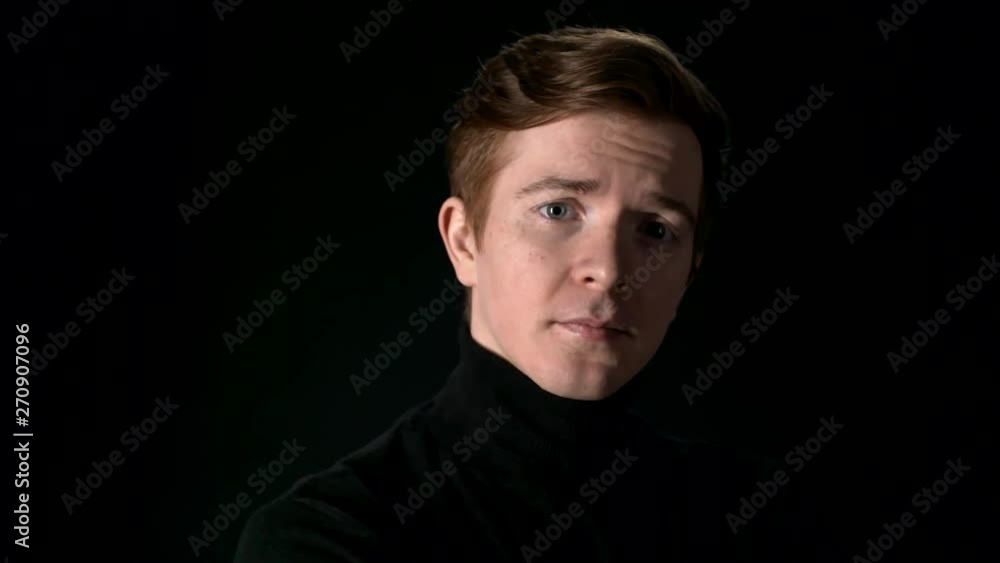 Lockdown of young Caucasian man turning to camera and looking at camera with serious expression on his face on black background Lockdown of young Caucasian man turning to camera and looking at camera with serious expression on his face on black background