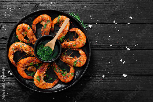 Tasty appetizing roasted shrimps prawns with spices and green sauce.