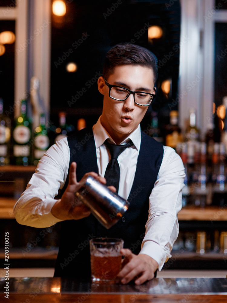 barman at work. A young bartender works with a shaker. Prepares delicious alcoholic cocktails barman at work. A young bartender works with a shaker. Prepares delicious alcoholic cocktails
