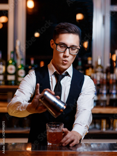 barman at work. A young bartender works with a shaker. Prepares delicious alcoholic cocktails