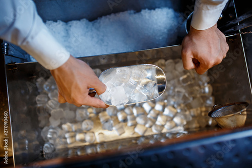 bartender scoops up ice for making alcoholic cocktails. close-up photo