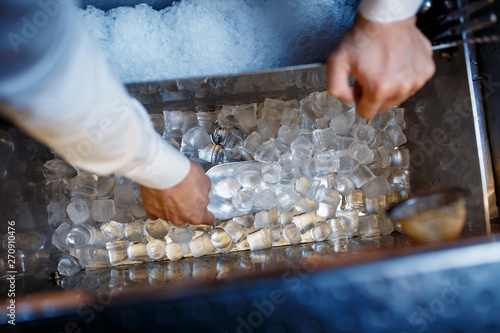 bartender scoops up ice for making alcoholic cocktails. close-up