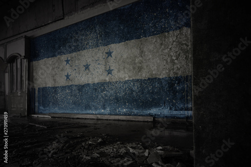 painted flag of honduras on the dirty old wall in an abandoned ruined house.