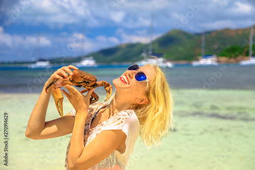 Tourism in Seychelles, Africa, Indian Ocean. Happy tourist woman holding an Ocypode Ceratophthalmus also called Ghost Crab with one claw being larger than the other. Curieuse Island Nature Reserve. photo