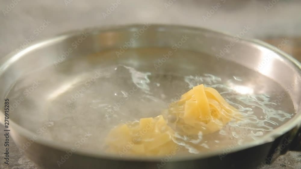 Food cooking. Italian pasta recipe. Chef throwing fettuccine nests in boiling water. Food cooking. Italian pasta recipe. Chef throwing fettuccine nests in boiling water.