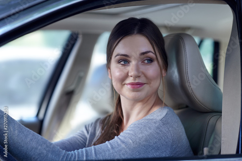 Young attractive caucasian woman behind the wheel driving a car. Happy smile, positive emotions. Copy space.