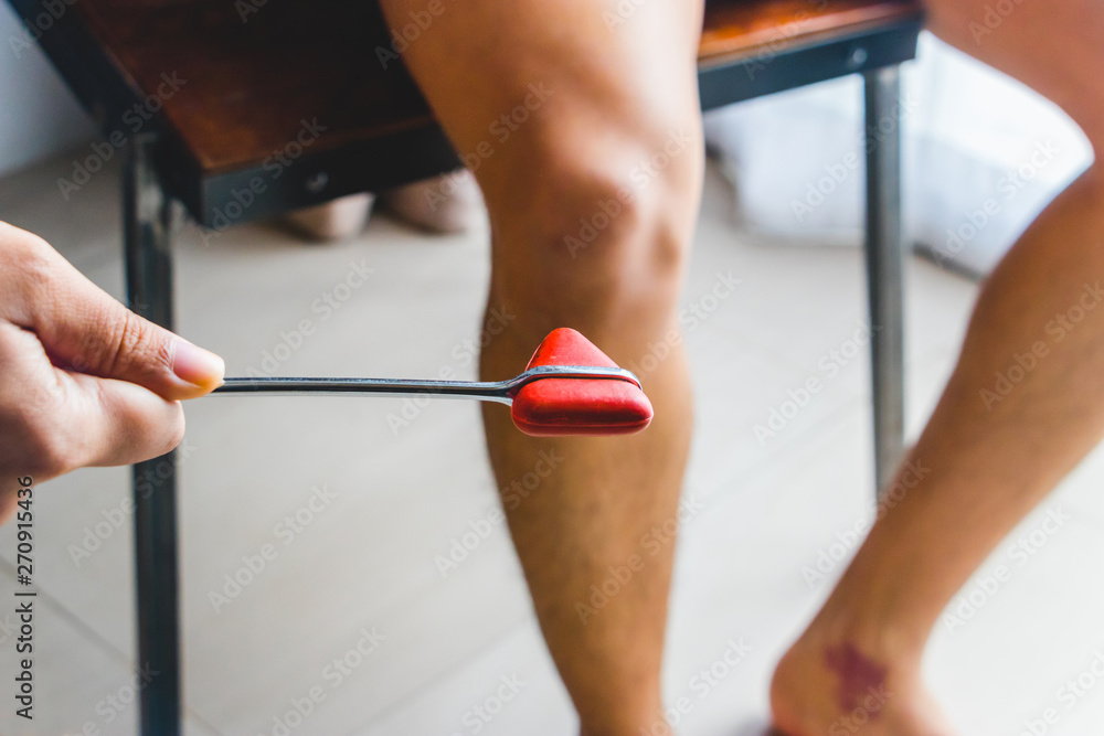 Doctor Testing Patellar Reflex Or Knee jerk Reflex With Red Hummer Jerk