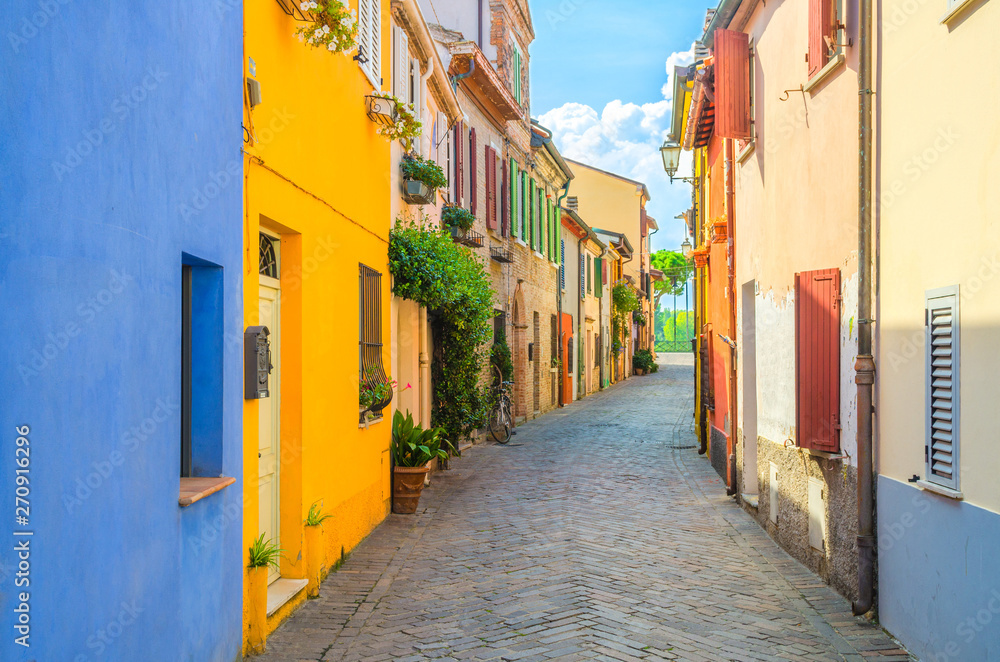 Typical italian cobblestone street with colorful multicolored buildings, traditional houses with green plants on walls and shutter windows in old historical city centre Rimini, Emilia-Romagna, Italy