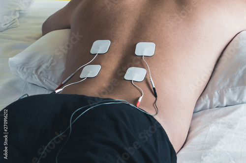 Patient applying electrical stimulation therapy on back. Electrical tens. photo