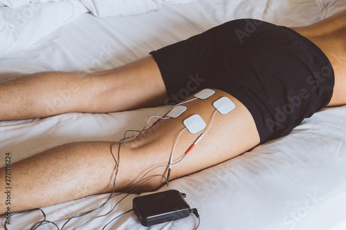 Patient applying electrical stimulation therapy on leg. Electrical tens.